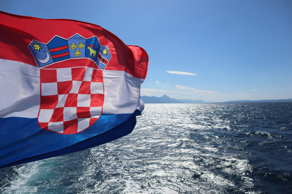 &lt;p&gt;Flag of Croatia over the sea against the backdrop of the sea coast, mountains on the horizon, blue sunny sky&lt;/p&gt;