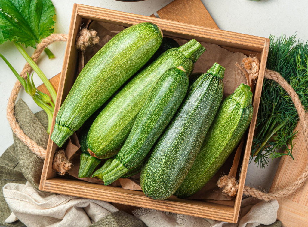 Slicing zucchini on a cutting board. Ripe zucchini on a gray background. Top view, horizontal.