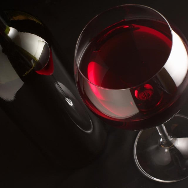 &lt;p&gt;Glass of red wine and bottle on black background.&lt;/p&gt;