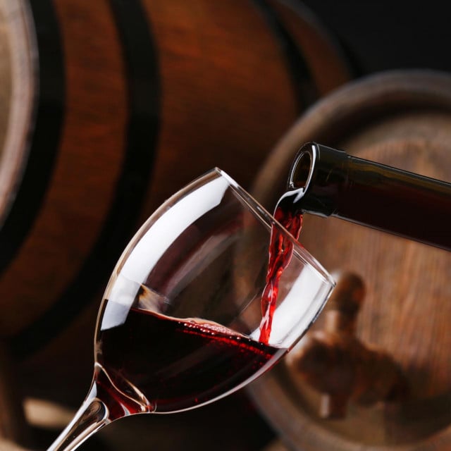 &lt;p&gt;Pouring red wine from bottle into glass with wooden wine casks on background&lt;/p&gt;