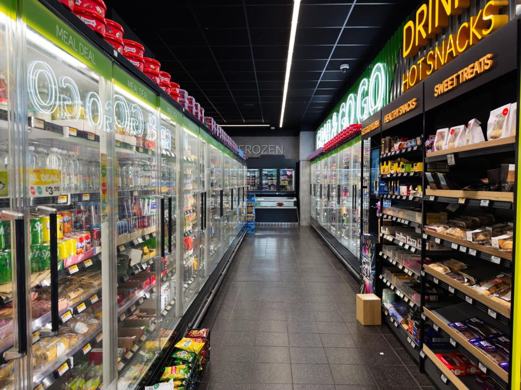 <p>Manchester, UK - September 25, 2025Vibrant SPAR grocery store aisle featuring cold drinks, snacks, and illuminated glass coolers in a busy setting.</p>