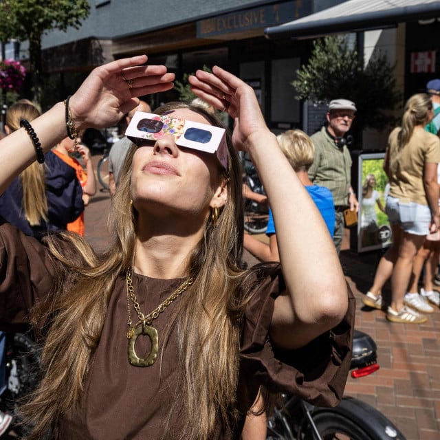 <p>A woman wears eclipse glasses in Almelo, eastern Netherlands on August 11, 2026 on the eve of a partial solar eclipse. The scramble for protective glasses has reached fever pitch across Europe ahead of August 12, 2026 rare total solar eclipse, as pharmacies, opticians and other shops struggled to keep them in stock. (Photo by Vincent Jannink/ANP/AFP)/Netherlands OUT</p>