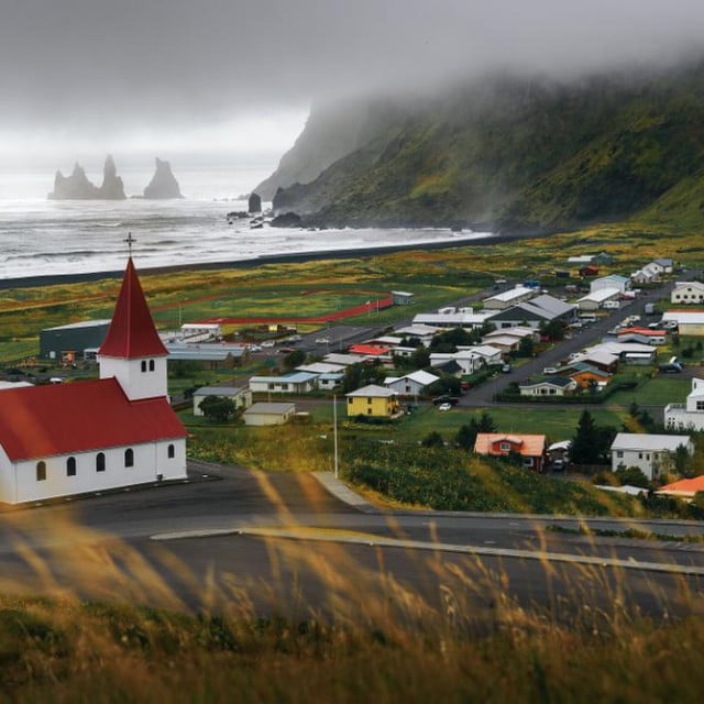 <p>Heavy clouds over the village of Vik and its lutheran church in Iceland with Reynisdrangar basalt sea stacks in the background.</p>
